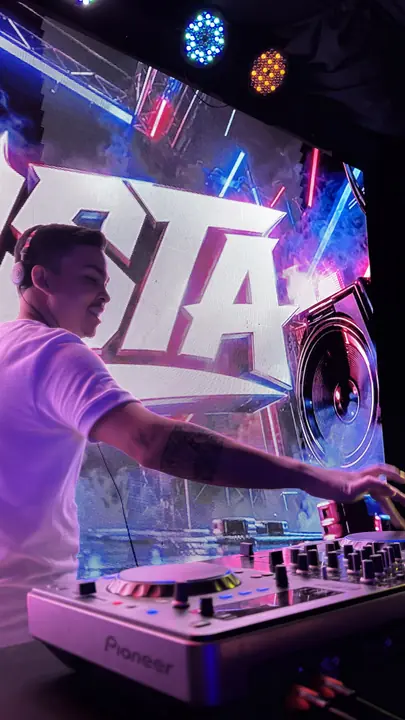 Gusta DJ tocando com o painel GUSTA ao fundo