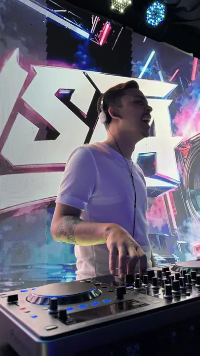Gusta DJ na frente do painel de LED com o nome GUSTA